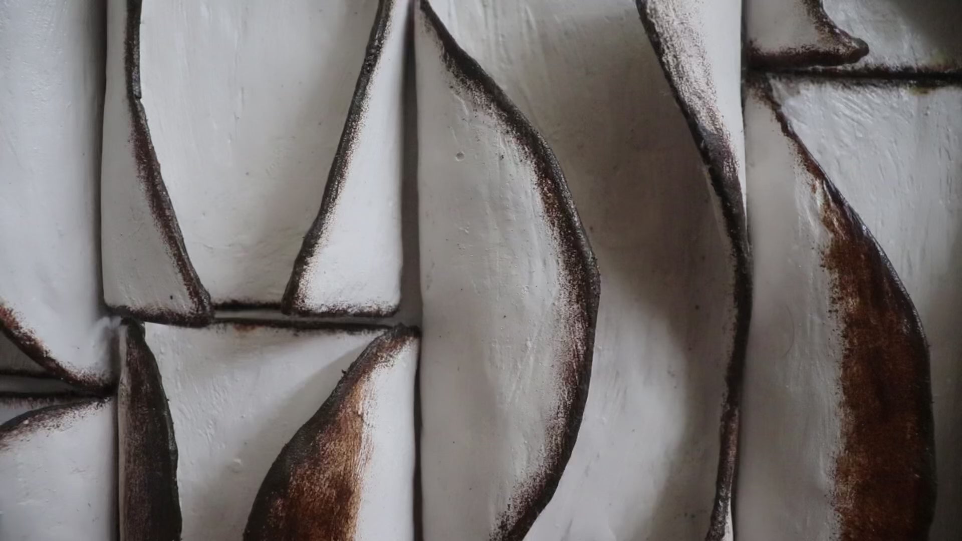 Video walkthrough of a sculptural 3D ceramic wall art installation in a luxury living room, showing how light and shadow move across the textured surface